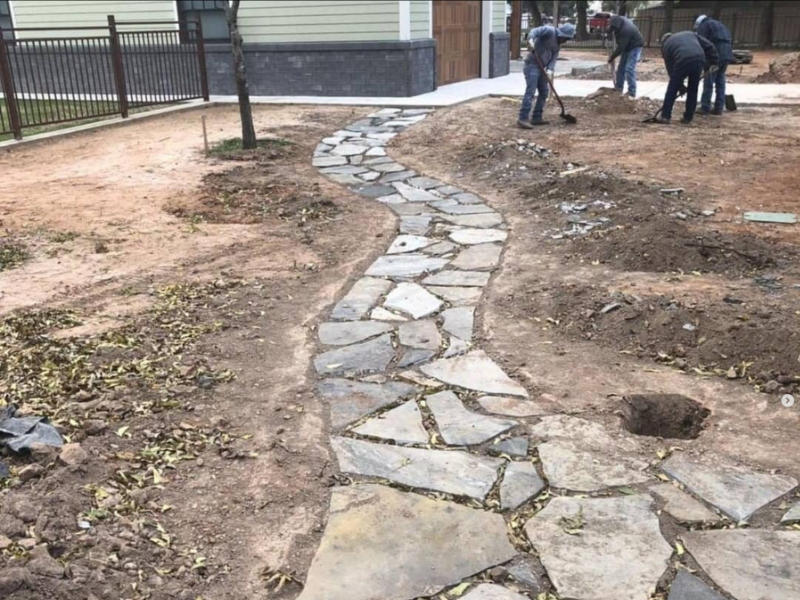 A team of professionals remodeling a front yard next to a new flagstone walkway.