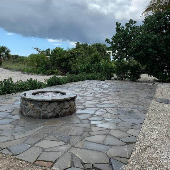 A flagstone patio with a fire pit made of natural stone.